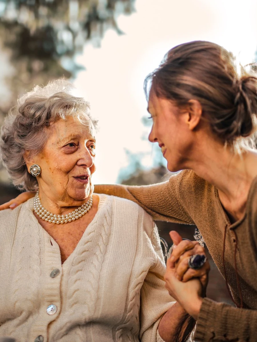 Adult daughter talking with her smiling elderly mother