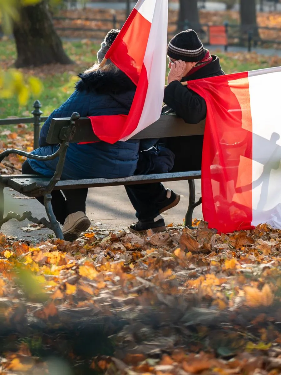 Couple on a park bench in Kraków with Polish flags
