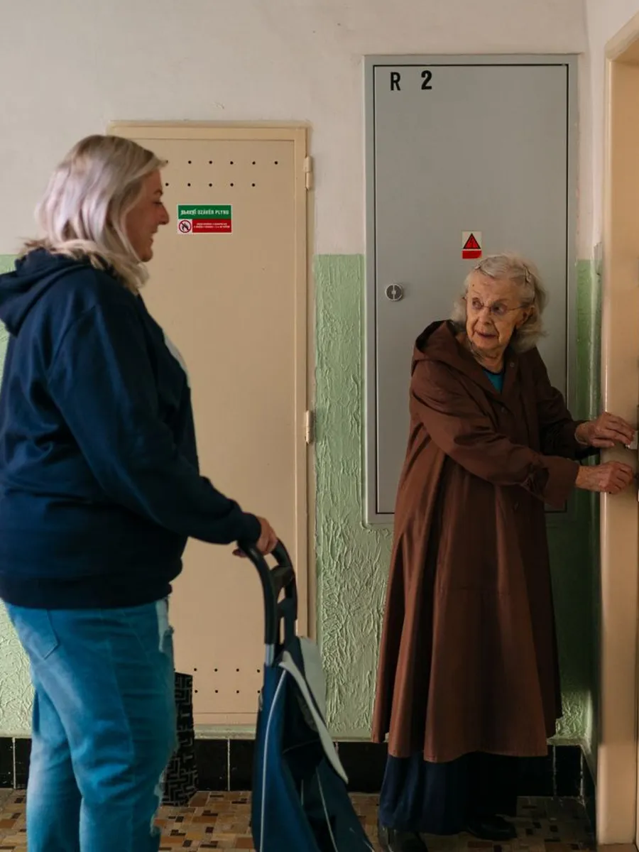 Older woman at the lift door chatting with a younger neighbour