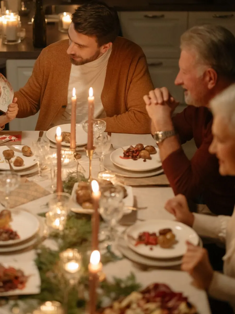 Man at a candlelit Christmas Eve table with his partner's family